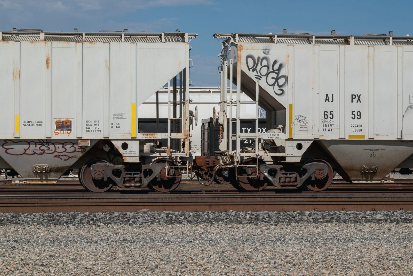 Two white covered hopper cars coupled together, seen side on